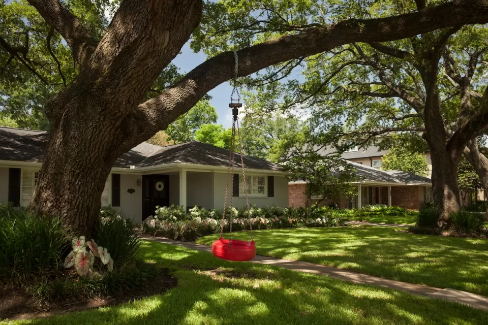Small house with a red tire swing in front yard in Houston, Texas.